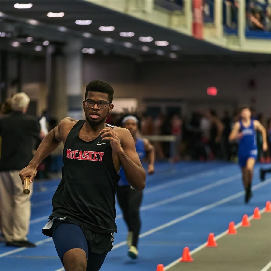 Isaiah running the anchor leg of a relay at an indoor track meet